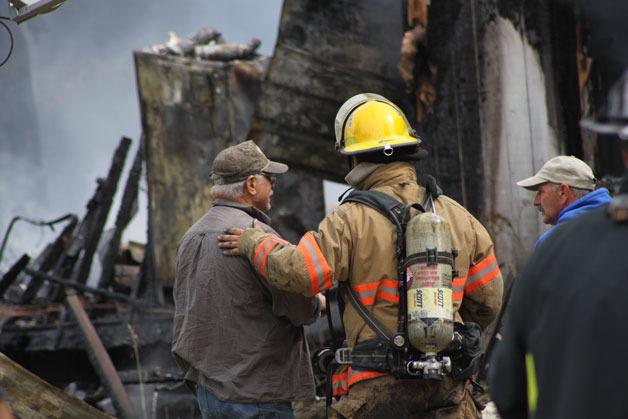 A firefighter with North Whidbey Fire & Rescue consoles Bruce Silvia after a fire that gutted his Coupeville home Sunday morning