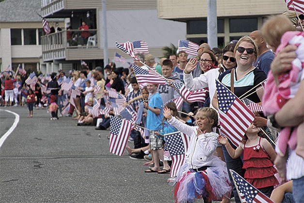 Spectators show their patriotism as they wave flags along Bayshore Drive to celebrate the Fourth of July grand parade in Oak Harbor Thursday. Weather was ideal for the occasion with sunshine and temperatures in the mid-to-high 60s and continued to be pleasant into the evening for the fireworks show.