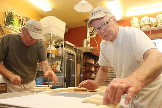 Larry Lowary places croissants onto a baking sheet while Gerry Betz rolls together pain au chocolat in their Clinton home bakery