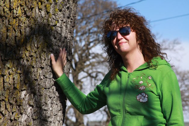 Laura Renninger of Oak Harbor stands next to a Garry oak tree in her neighborhood that her family has identified with for two decades as the 'turn-around' tree. She started a group to help preserve Garry oaks called the Oak Harbor Garry Oak Society.
