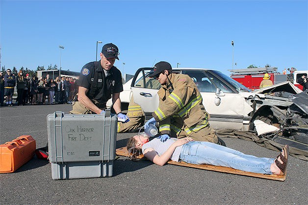 Oak Harbor Fire Department Captain Craig Anderson and firefighter Gen Cox perform live-saving measures on Oak Harbor High School senior Ella Brooks. Officials hope showing students the repercussions of bad choices will save lives.