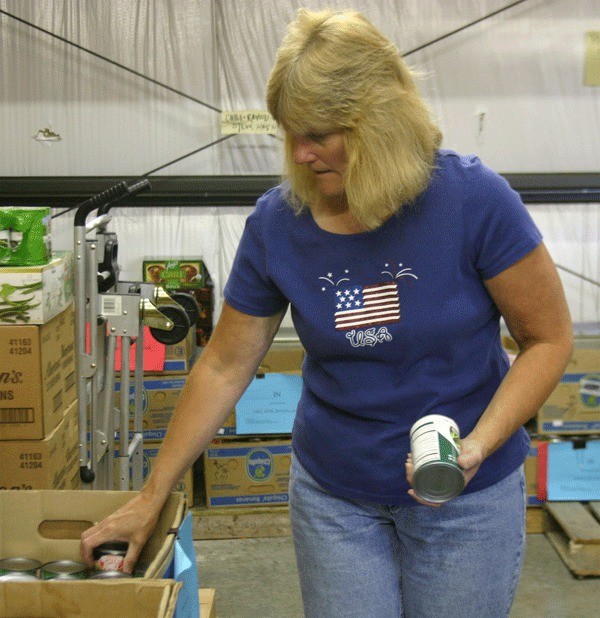 North Whidbey Help House Executive Director Jean Wieman sorts food in the warehouse on Tuesday. This Saturday the organization will be holding its annual Christmas in July fundraiser to try and stock some empty shelves during the slow summer months.