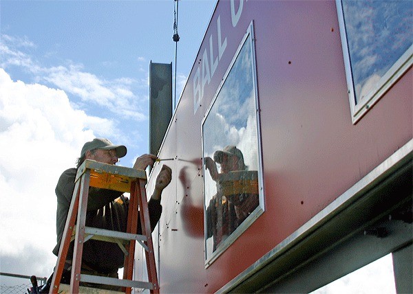 Pat Andrews of CK Electric Services helps install a new scoreboard at Mickey Clark Field.