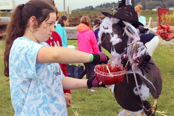 Amber Ramirez and fellow Oak Harbor Girl Scouts decorate scarecrows at Dugualla Bay Farms Friday evening. The Halloween-themed activity was a part of the girls’ annual peanut butter and jelly drive to benefit the Help House.