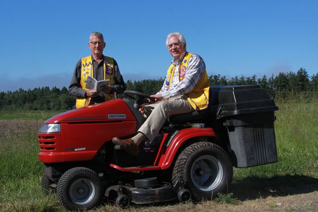 Joe Hillers and Julian Sayers of the Coupeville Lions Club try out a riding lawnmower that will be for sale at the annual Lions Garage Sale June 27-28 at Coupeville Elementary School.
