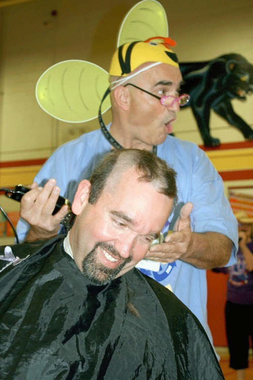 Oak Harbor Middle School Principal Shane Evans gets his hair chopped by science teacher and de facto school barber Alan Bailey Friday morning as part of a fundraiser for Relay For Life.
