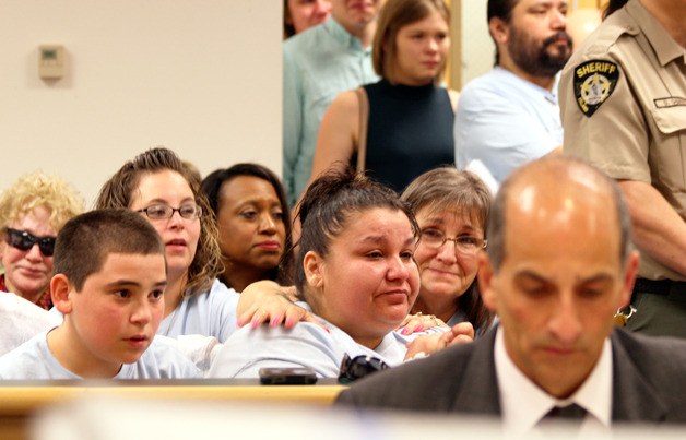 Bettie Sifuentes is comforted by Christina Baker as the man who killed her son is sentenced to prison Friday. Island County Prosecutor Greg Banks is in the foreground. The courtroom was packed with people demanding justice for Adam Garcia.