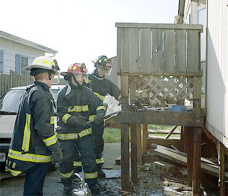Central Whidbey firefighters break apart a charred deck at a trailer park off SW Terry Road in Coupeville. Fire Chief Ed Hartin said residents were barbecuing on the deck and the small fire was likely caused by ashes. It was extremely windy at the time but fortunately the fire did not spread. No one was injured and the mobile home was unscathed.