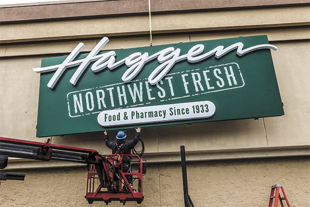A worker helps install a new Haggen banner in front of the former Albertsons store in Monroe earlier this month.
