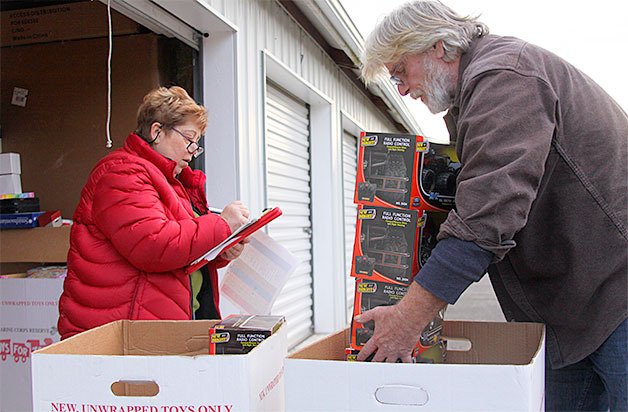 Re McClung checks off inventory as Bill Smith loads toys for delivery at a storage unit in North Whidbey.