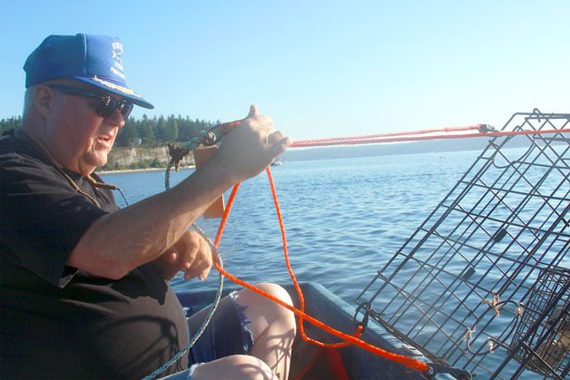 Dave Anderson of Coupeville prepares to drop a crab pot into Holmes Harbor last July. The 2016 season starts Friday in waters around Whidbey.