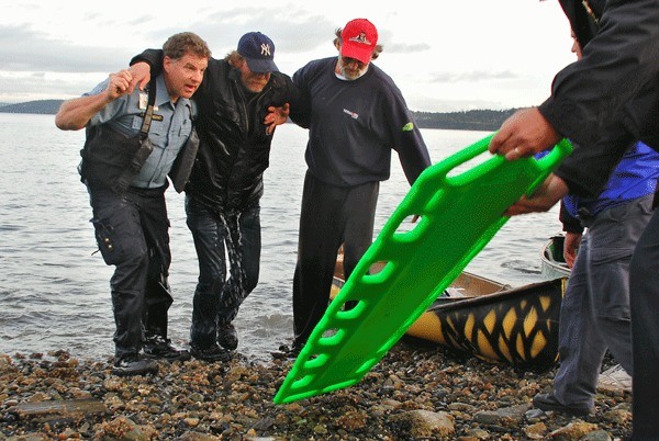 Whidbey General Hospital paramedic Ian Tully and Madrona Way resident Mark Rasmussen haul a man to safety after he spent about 30 minutes clinging to the side of his canoe in Penn Cove.