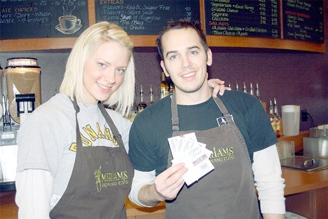 Miriam's Espresso employee Megan O’Halloran stands with Jared Rusnak as he displays several of the Central Whidbey First cards that businesses in town have promoted for nearly a year.