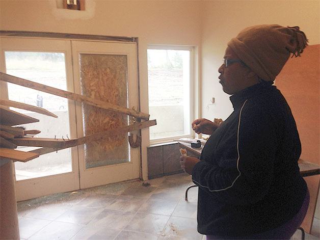 Pastor Fannie Dean stands in front of a glass door that was broken with a thrown rock Friday.