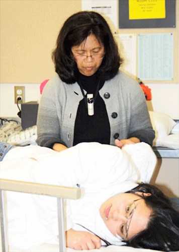 Human Body and Medical Careers Internship teacher Fil Jepsen demonstrates how to change an occupied bed as senior Theresa Hicks acts as a patient.