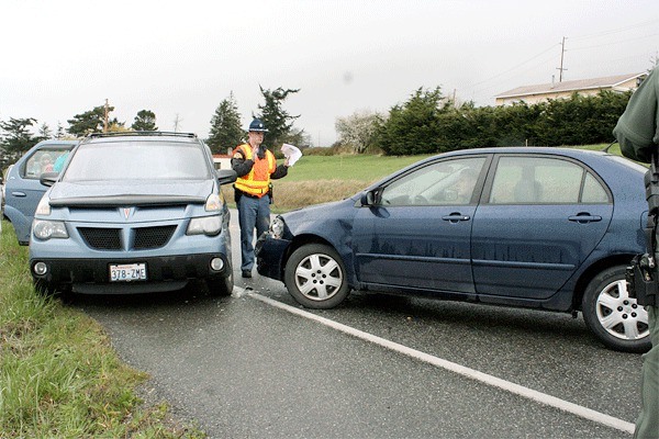 Washington State Patrol Trooper Chris Merwin directs a car after it collided with a SUV Wednesday afternoon on Highway 20 near the intersection of Arnold Road.