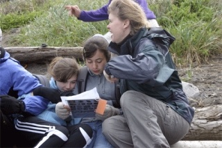 Seventh-graders Maddy Mosolino and McKenzie Schneider along with parent Paige McGuire study tide pool charts while fighting off a chilly breeze.