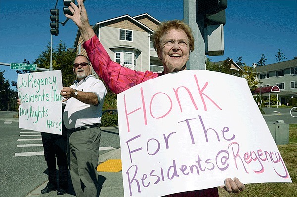 Jan Ellis and Bill Noack wave homemade protest signs in front of Regency on Whidbey Monday afternoon. They are mad about recent staff changes and have disagreements with management of Regency's assisted living facility.