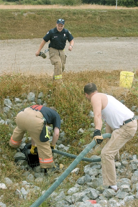 North Whidbey Fire and Rescue firemen flush the charred culvert pipe.
