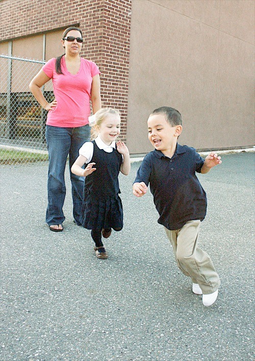 New kindergarteners Cianna Christ and Colin Shishido chase each other in circles as a parent looks on before the beginning of the first day of school Thursday.