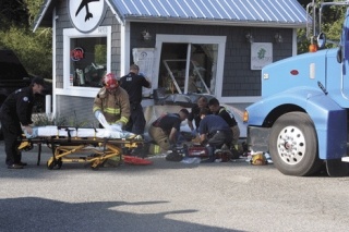 Firefighters from North Whidbey Fire and Rescue along with paramedics perform CPR on a truck driver who ran into an espresso stand at Liberty Market Monday morning located north of Oak Harbor.