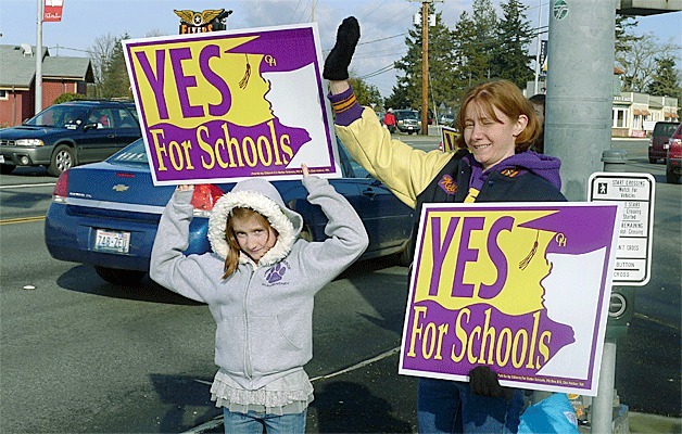 Kenyon and Katie Blaine wave signs Sunday in support of a levy that will bring millions of taxpayer dollars to the Oak Harbor School District. Ballots for the mail-in election had to be postmarked by Feb. 12 to be counted.