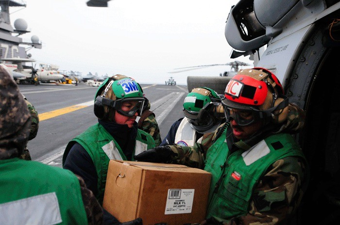 Sailors load food and water onto an HH-60H Seahawk helicopter on the flight deck of the aircraft carrier USS Ronald Reagan.