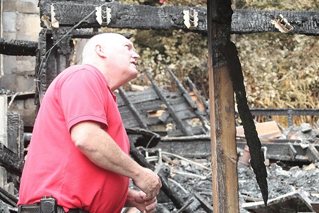 Oak Harbor Fire Chief Ray Merrill investigates the scene of a Central Whidbey house fire that killed a resident early Saturday morning. The body of former dentist Michael Nieder was discovered among the fire remains.