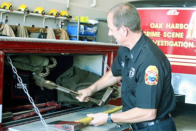 Lt. Don Baer with the Oak Harbor Fire Department demonstrates the difficulty in finding and retrieving rescue equipment from the crammed compartment of the rescue aid truck the department is replacing.