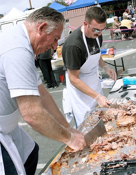 Jim Christian and Justin Krueger chop away at pork that was served at the second annual Fidalgo Avenue Block Party in Oak Harbor. Volunteers served 1