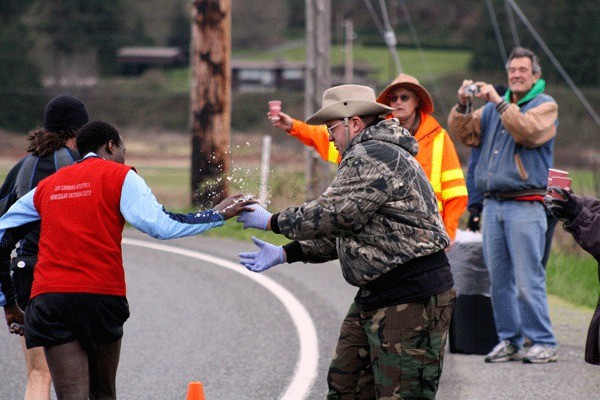 A marathoner grabs a cup of water on-the-run at the IDIPIC-sponsored aid station on Dike Road.