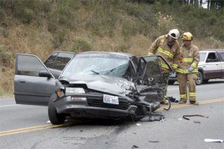 Firefighters inspect a car that was badly damaged in a accident on Highway 20