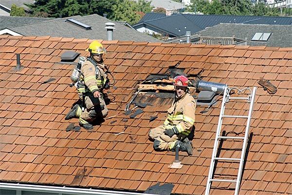 Firefighter Ricardo Quevas and Lt. Craig Anderson of the Oak Harbor Fire Department examine the damage to a roof after they extinguished a fire on Fairhaven Drive Thursday afternoon.