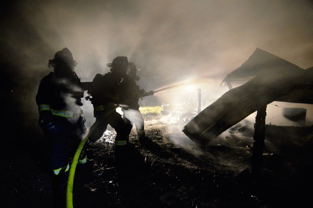Firefighters with Central Whidbey Island Fire and Rescue extinguish a mobile home on Race Road that caught fire Sunday night.