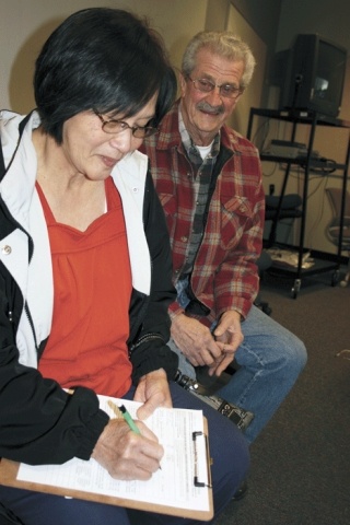 Erlinda Say of Oak Harbor fills out an intake form as Al Braley of Oak Harbor looks on. Say has filed her taxes through the AARP program for the last four years.