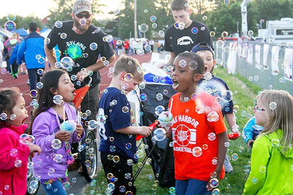 Children take a break from walking during the Relay for Life event Friday to play in bubbles created by a bubble machine on the outside of the track. Left