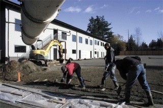 Workers from Concrete Nor’West smooth out wet cement as they finish a sidewalk Thursday morning in front of the Oak Harbor building that will house the new Waste Management regional customer service center employing 120 people.