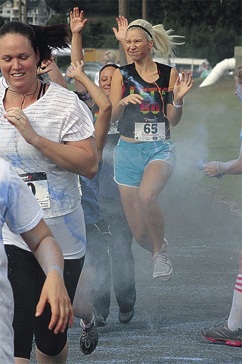 Runners react to being showered with colored powder during Saturday's Run IN Color 5K.