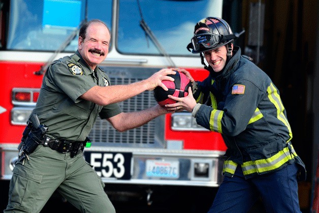 Island County Sheriff’s Deputy Chris Garden and Central Whidbey Fire and Rescue Firefighter Jerry Helm pretend to wrestle for control of a basketball. Island police and firefighters will square off in a game of hoops next Saturday to raise money for Coupeville Pastor Garrett Arnold.
