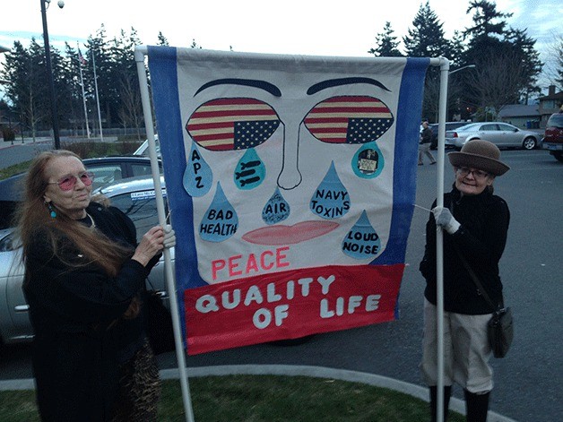 Concerned Island Citizens members Mari Anderson and Wendy Campbell DeWinter hold a sign outside of Oak Harbor High School during an EIS public meeting last week.
