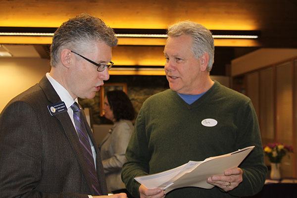 Oak Harbor Public Schools Superintendent Lance Gibbon chats with Paint Your World owner Ron Apgar at an open house last week at the high school with local business leaders.