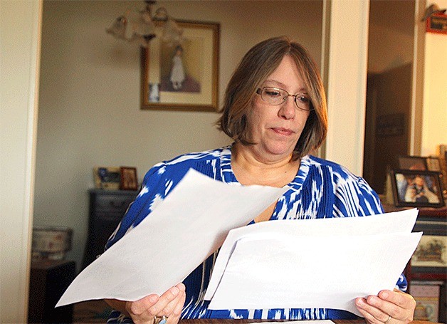 Coupeville resident Luanne Raavel looks through police reports of her son’s assault Tuesday morning. She obtained the paperwork after a deputy prosecutor declined to file charges against the suspect.