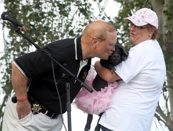 Island County Sheriff Mark Brown kisses a pig held by 911 dispatcher Kelly Crownover during the Big Kiss Off Challenge. The Island County Sheriff’s Department raised about $300 more for United Way than its competitor