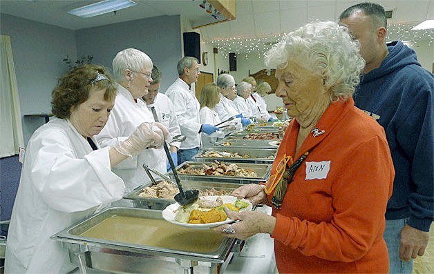Oak Harbor resident Ann Liszak gets a plate full of food Thursday during the North Whidbey Community Harvest. She enjoyed a Thanksgiving feast before volunteering in the afternoon.