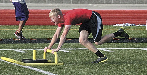 Oak Harbor's Nate Stanford pushes a prowler sled during summer workouts.