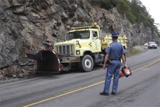A trooper watches as a state Department of Transportation plow pushes a small rockslide off Highway 20 at Deception Pass Thursday afternoon.