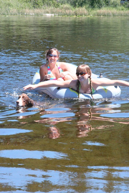 Laura Utter and Sierra Roe paddle in an inflatable boat while their English springer spaniel