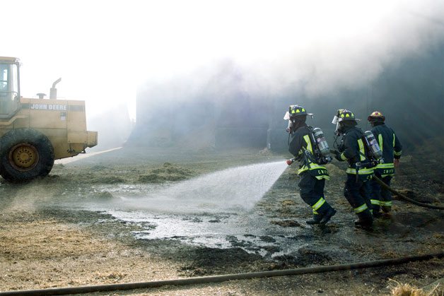 Firefighters douse smoldering hay next to the historic Engle Farm barn in Central Whidbey Thursday afternoon.
