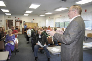 ABOVE: Island County Commissioner Mac McDowell addresses a packed room of residents Thursday evening in Oak Harbor at a community meeting as he explains the rationale behind the county’s “aircraft accident potential zone” ordinance passed in March. Many of the citizens sounded off on what they believed were unfair regulations. AT LEFT: Oak Harbor resident Paul Bovey poses a question Thursday evening to county representatives. A lively community meeting was held to discuss the ordinance.