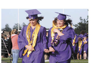Immah Harless and Jenna Marin brave wind gusts through Wildcat Memorial Stadium during Oak Harbor High School’s graduation ceremony that took place Monday.